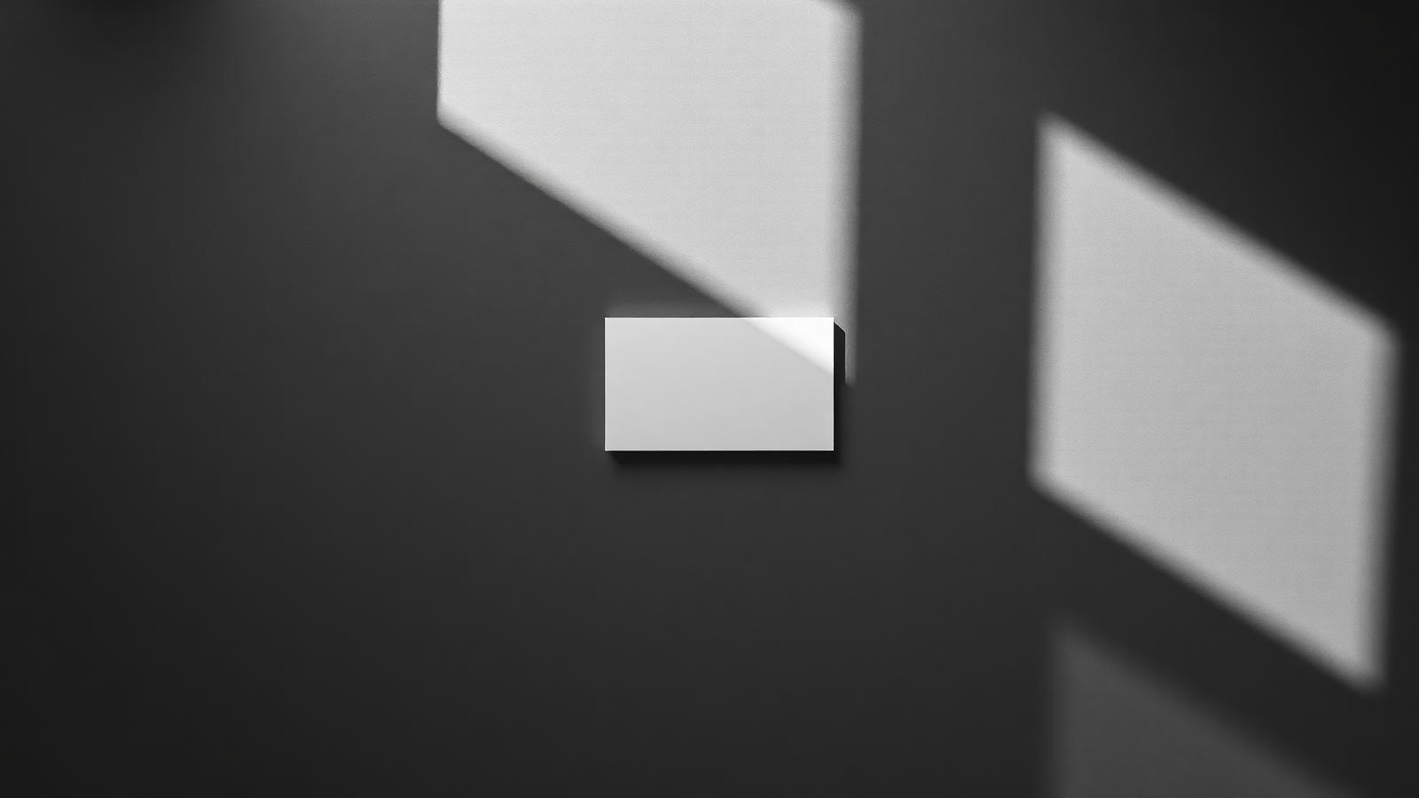 A single white card lit by hard directional light on a dark surface